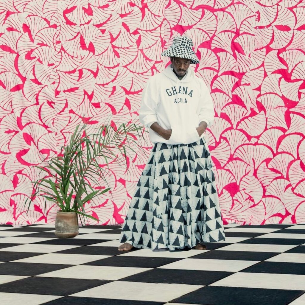 Man wearing a bucket hat, sweatshirt, and printed skirt