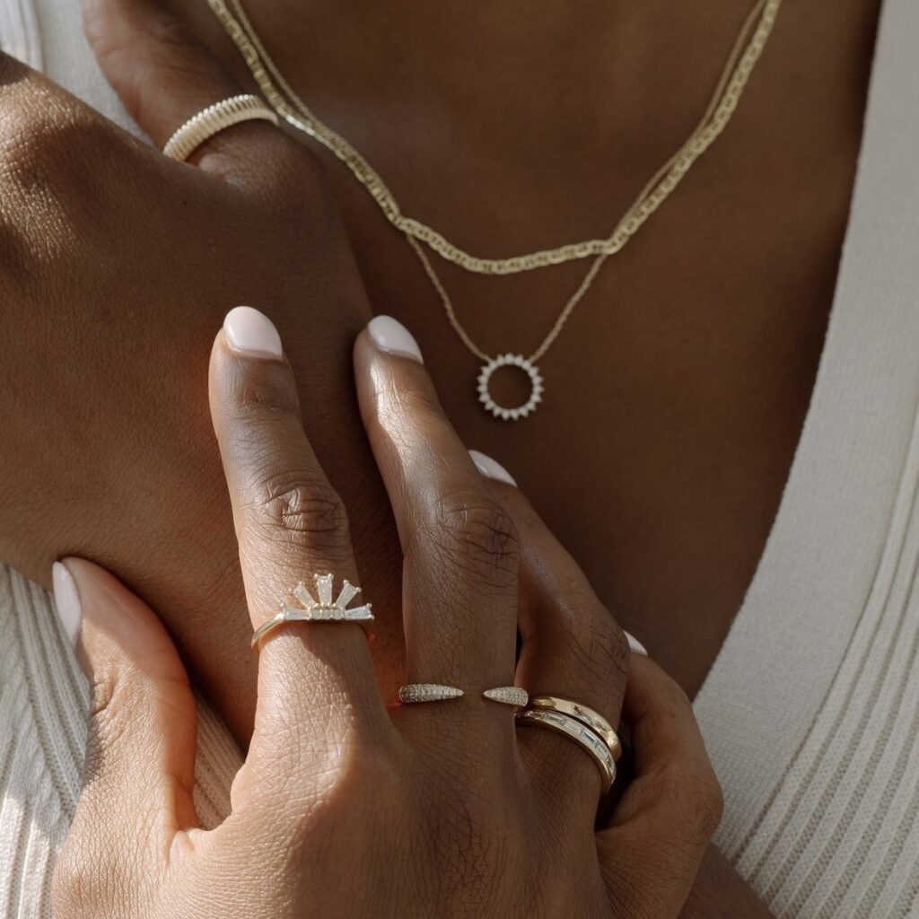 close-up of hand with gold rings and neck with gold necklaces