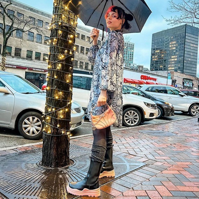 woman holding umbrella and small tan leather purse