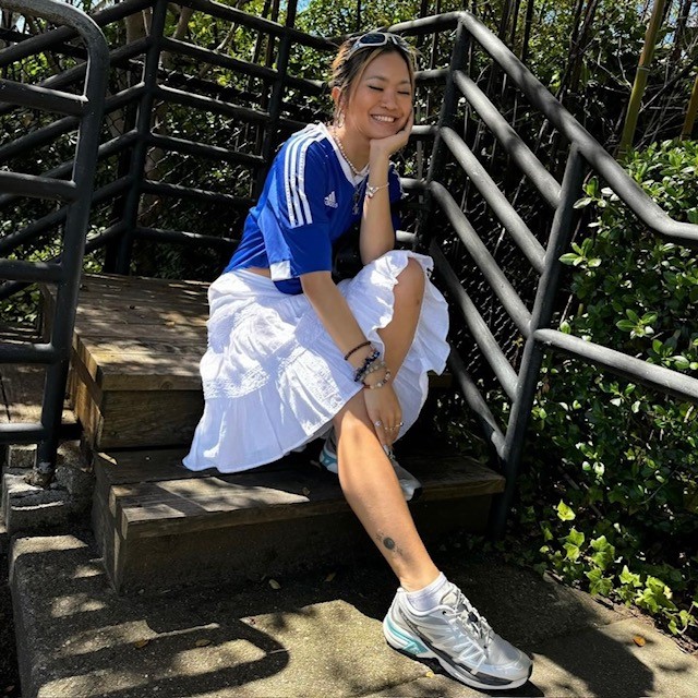 woman in sporty classic look with soccer jersey and pleated skirt