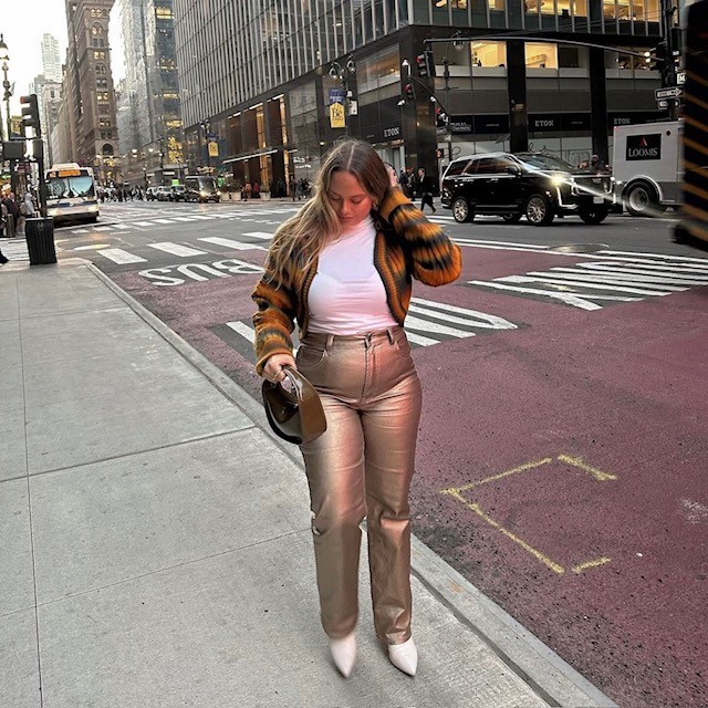 woman in gold metallic jeans, white t-shirt, and yellow cardigan