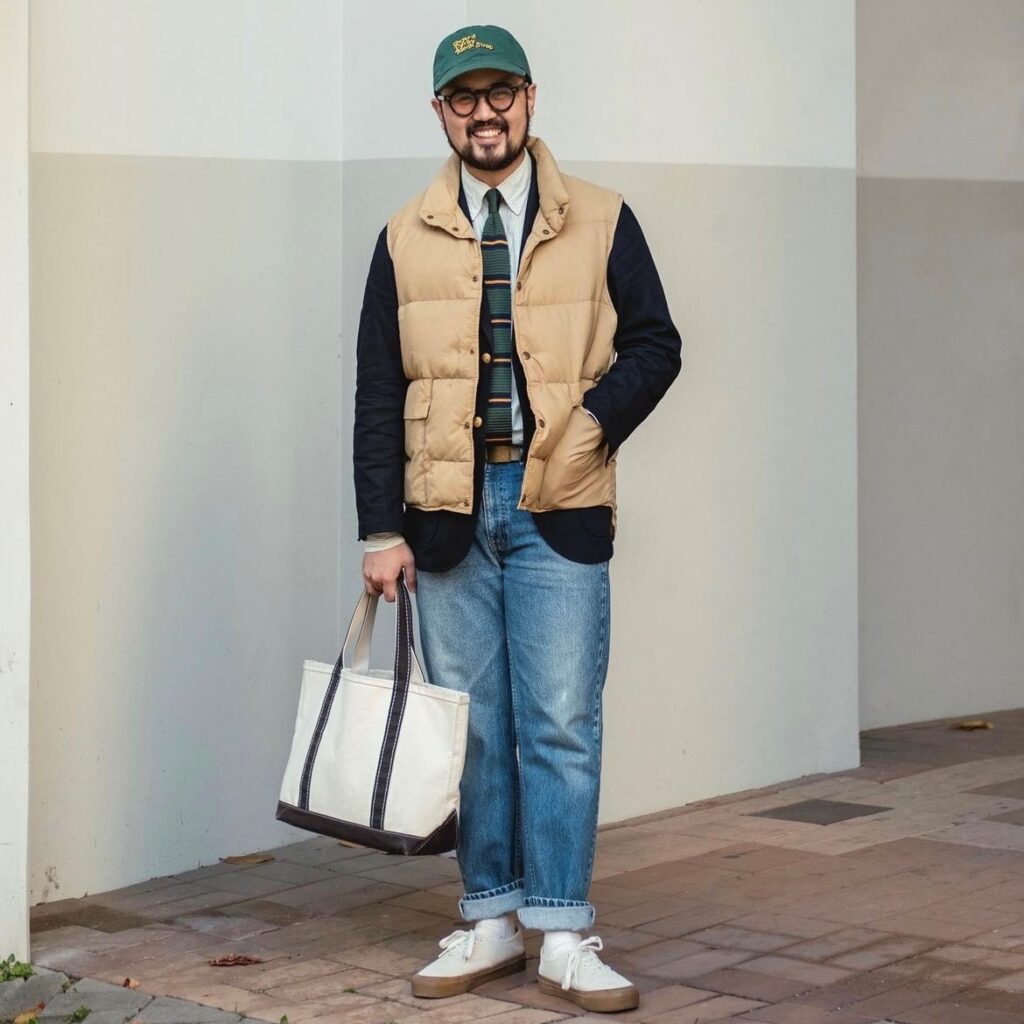 man wearing a puffer vest over blazer, button down, and jeans