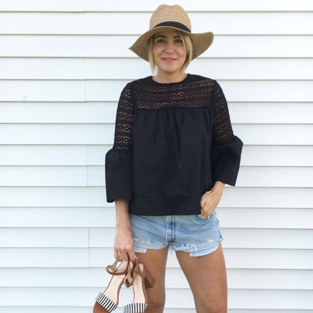 woman in black boho blouse and denim shorts