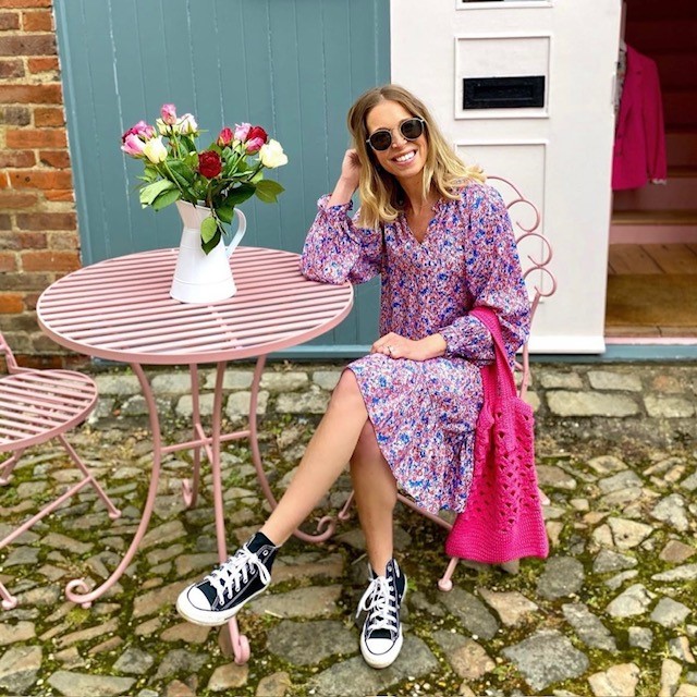 woman in pink and blue ditsy floral dress with black converse shoes 