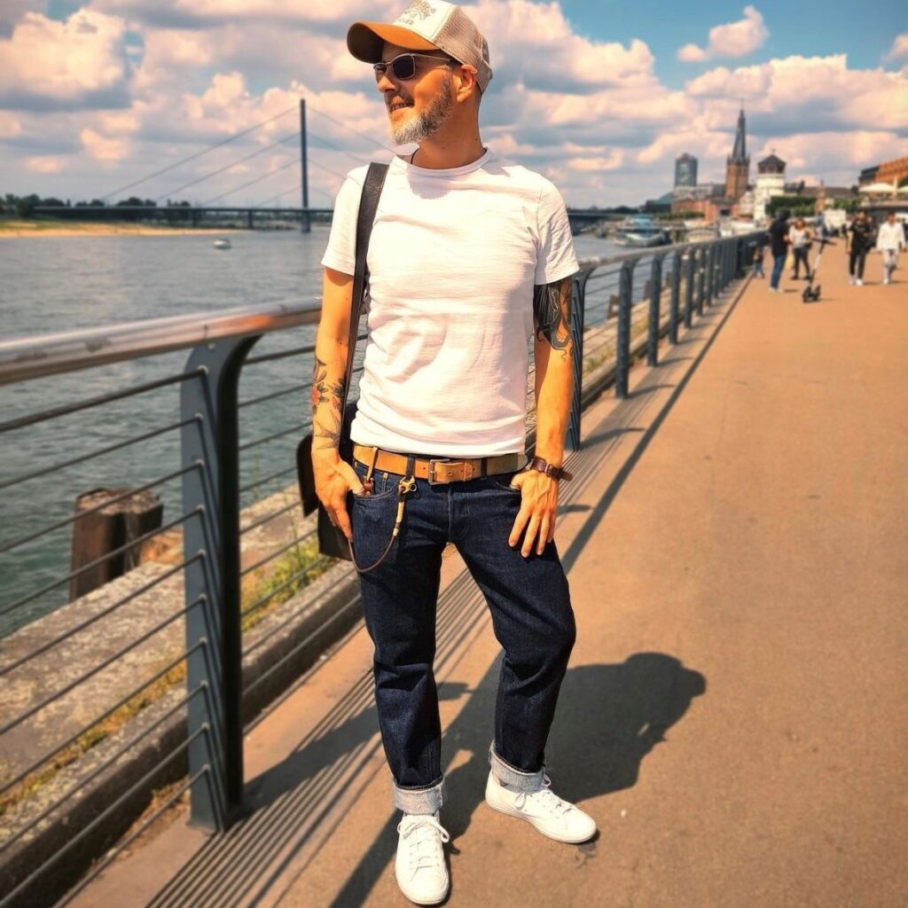 man wearing a white t-shirt, jeans, and white slim sneakers