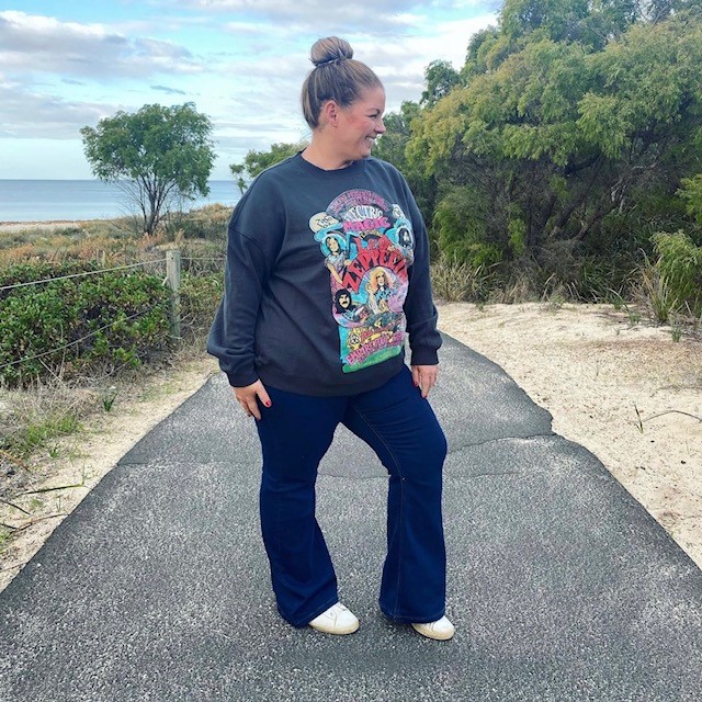 Woman wearing puddle jeans with white sneakers and black graphic sweatshirt