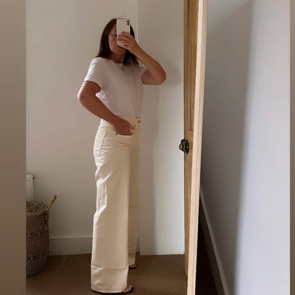 woman taking selfie in beige puddle jeans and white t-shirt