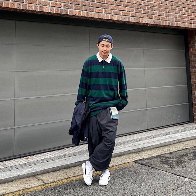 man with green and navy rugby shirt with oversized gray pants