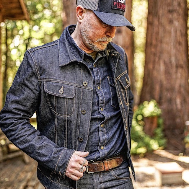 man wearing a denim shirt, jean jacket, jeans, and brown belt