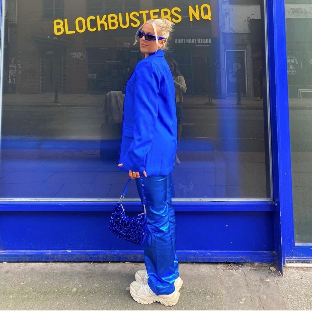 woman in blue pants with matching blazer and handbag