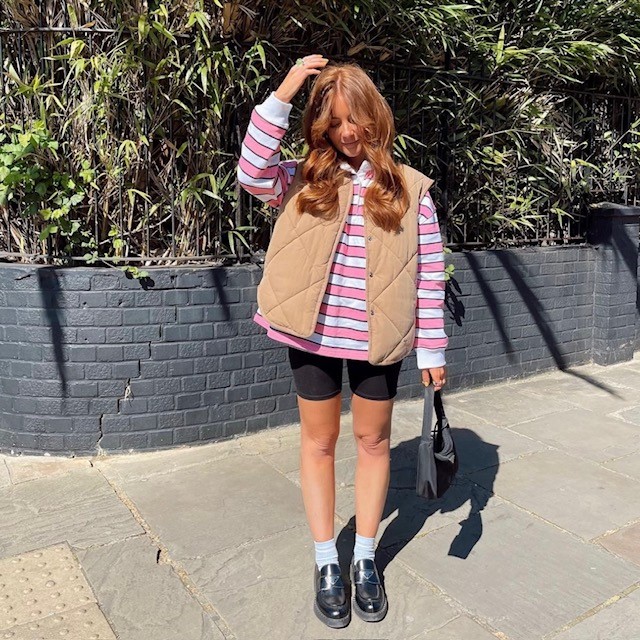 woman in a pink striped version with biker shorts and a tan vest