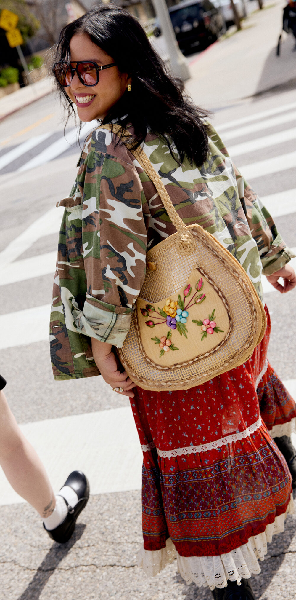 Andrea wearing a camo jacket and red patterned skirt smiling