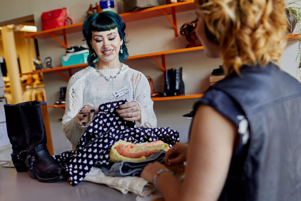 woman buying clothing from a customer in a secondhand shop