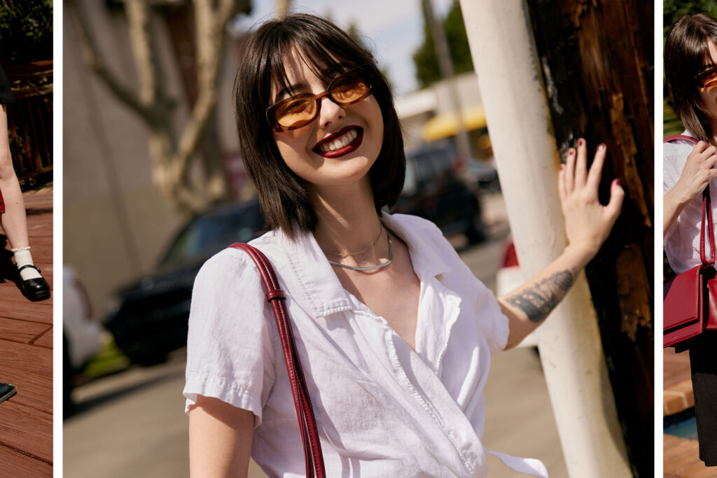 Cate wearing a white button up shirt and black skirt holding a red purse