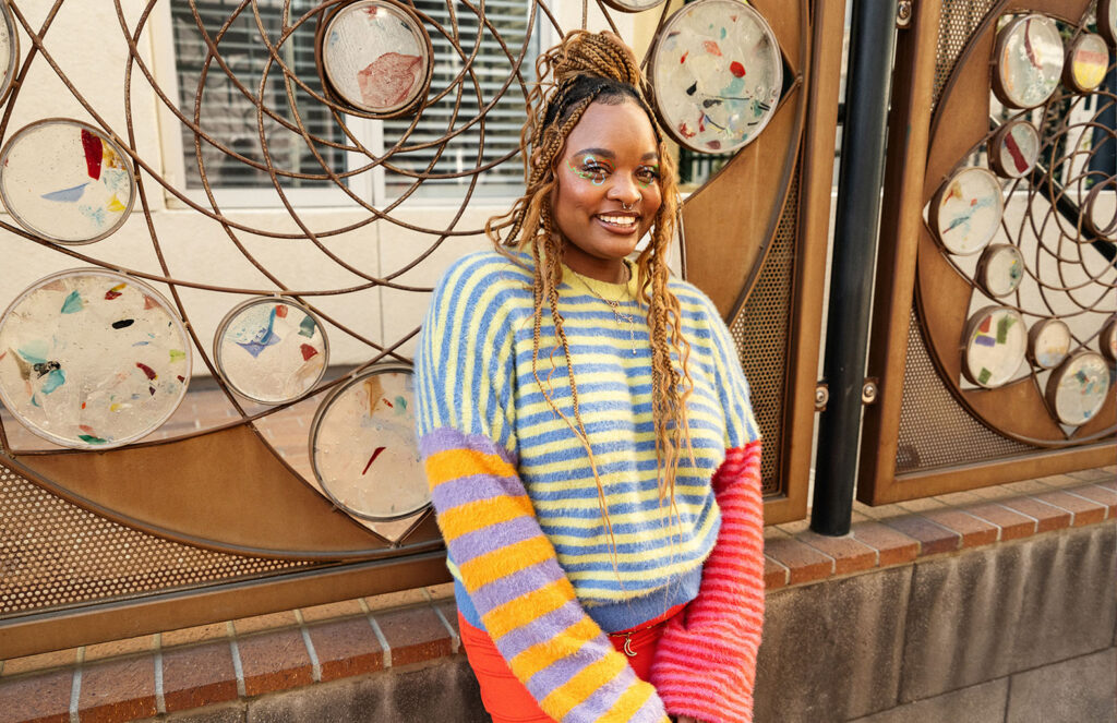 Erykah wearing a colorful striped sweater