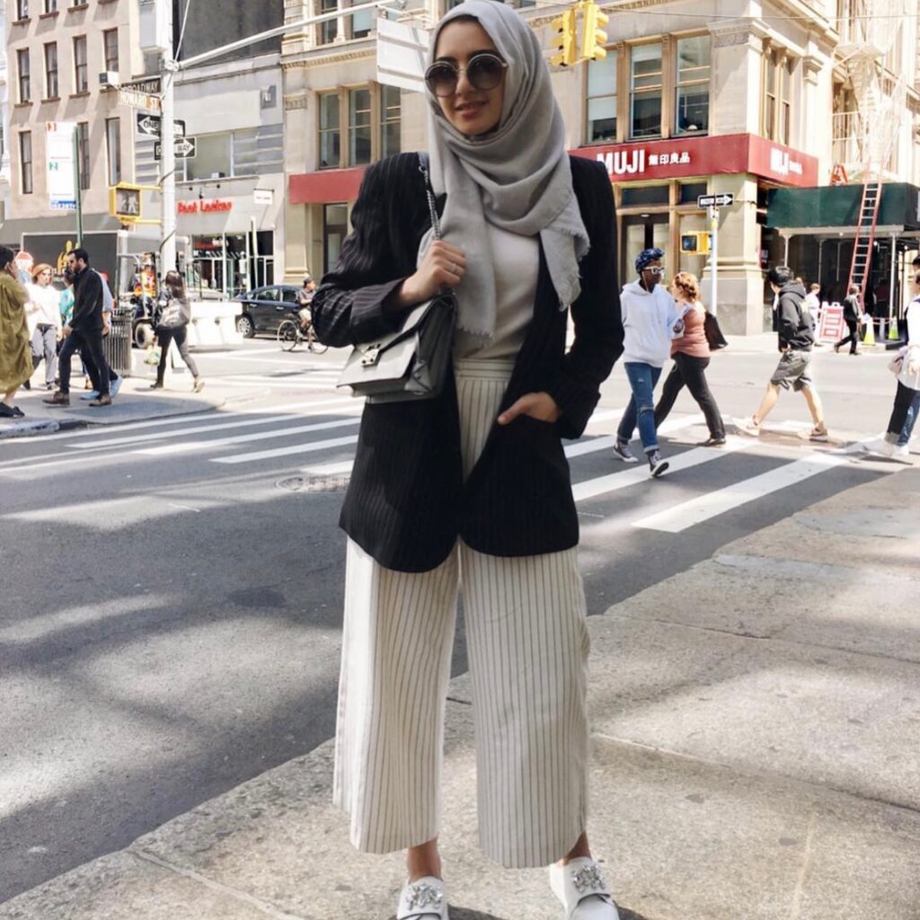 woman dressed in cream-colored cropped trousers, cream top, and black blazer