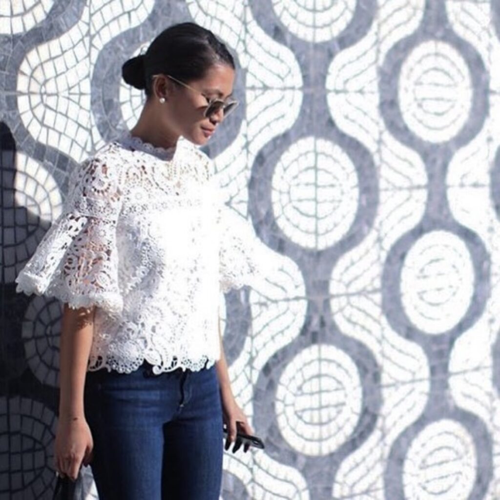 woman wearing a lace top with dark denim jeans